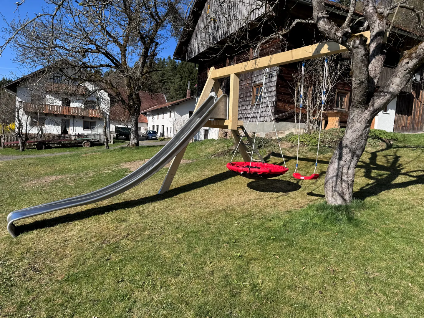 Spielbereich mit Rutsche und Nestschaukel am Hof